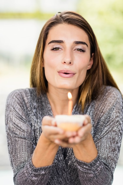 Portret pięknej kobiety mienia urodzinowa babeczka z jeden świeczką