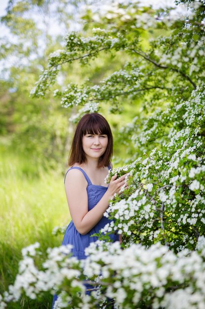 Portret pięknej kobiety pozuje z kwitnącym drzewem w letnim ogródzie