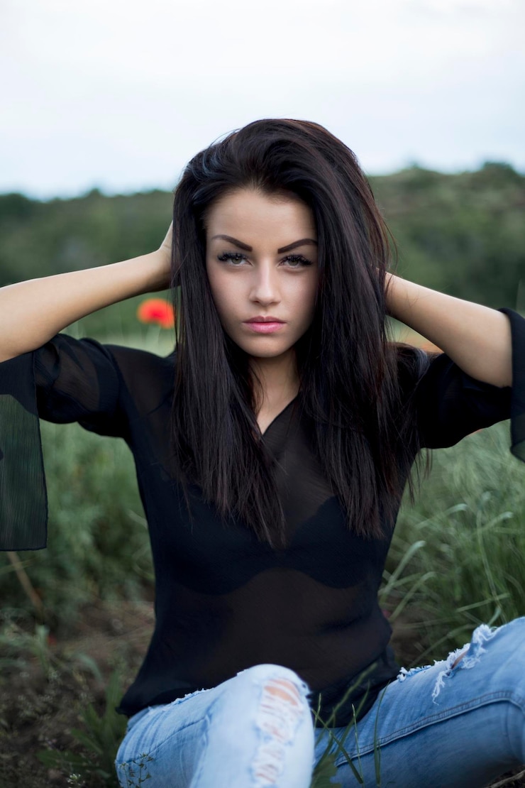 Zdjęcie portret pięknej kobiety siedzącej na trawiastym polu