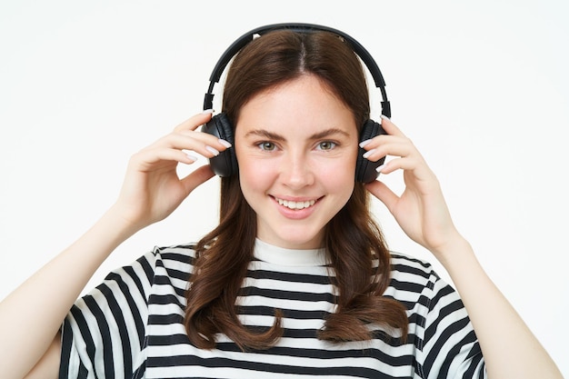 Zdjęcie portret pięknej kobiety w bezprzewodowych słuchawkach słuchającej muzyki za pomocą słuchawek uśmiechającej się do kamery