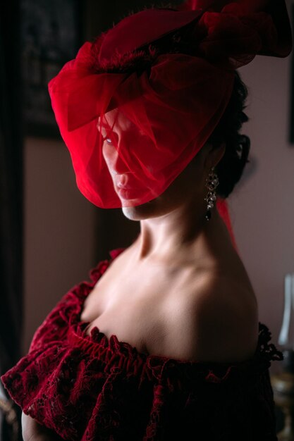 Portret pięknej kobiety w czerwonym kapeluszu vintage z wczesną odzieżą z welonem