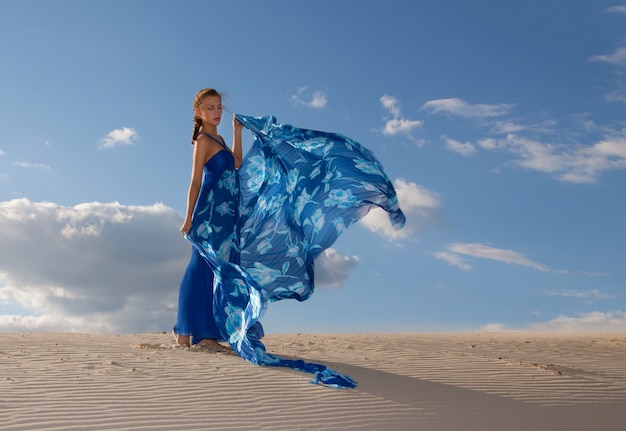 Portret pięknej kobiety w niebieskiej sukience na pustyni