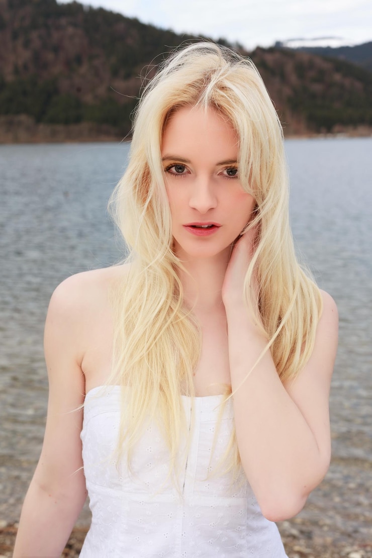 Zdjęcie portret pięknej kobiety z blond włosami stojącej nad jeziorem