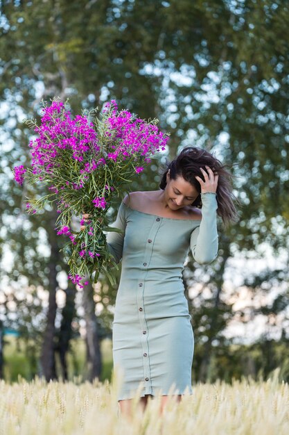 Portret pięknej kobiety z bukietem kwiatów spacerujących po polach
