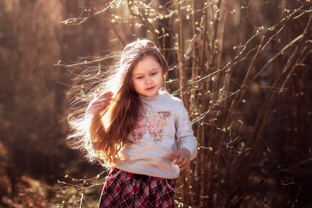portret pięknej małej dziewczynki z długimi włosami w lesie na przyrodę