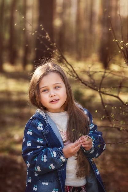 portret pięknej małej dziewczynki z długimi włosami w lesie na przyrodę