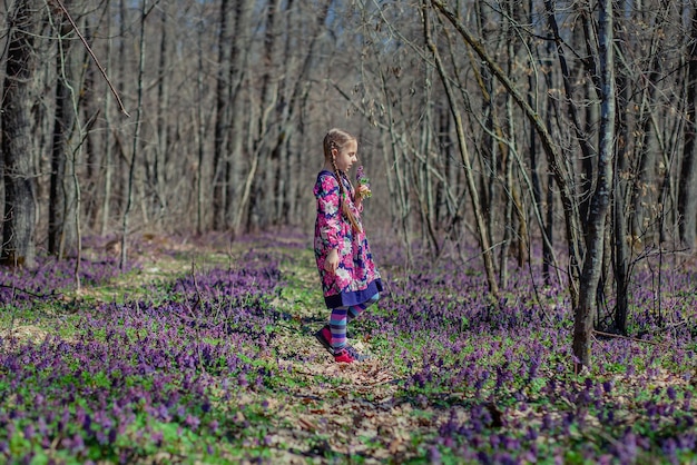 Portret pięknej małej dziewczynki z kwiatami corydalis