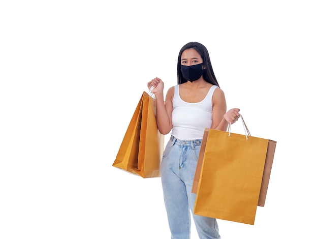 Portret pięknej młodej azjatyckiej kobiety noszącej maskę ochronną i trzymającej torby na zakupy na białym tle
