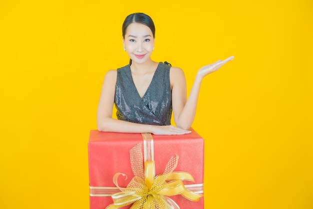 Portret pięknej młodej azjatyckiej kobiety uśmiech z czerwonym pudełkiem na żółto