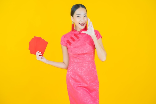 Portret pięknej młodej azjatyckiej kobiety z czerwoną kopertą na kolorowym tle