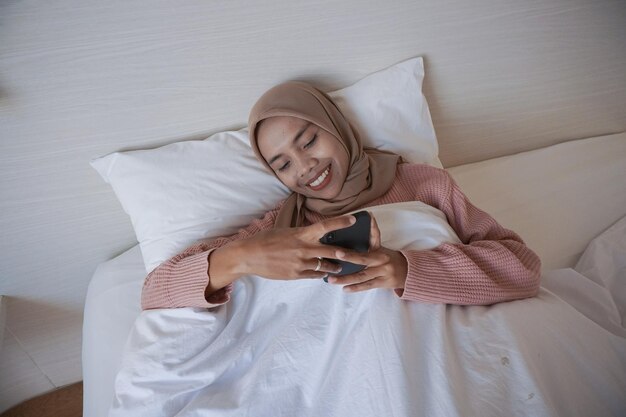 Portret pięknej młodej azjatyckiej muzułmanki w chustce na głowie leżącej w łóżku i śpiącej