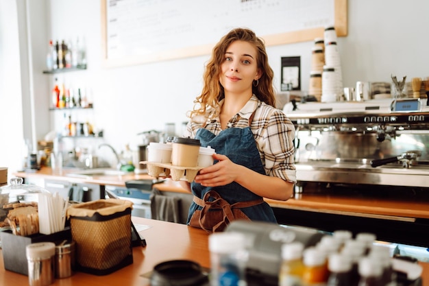 Portret pięknej młodej baristki serwującej kawę z dużym uśmiechem Właściciel małego biznesu
