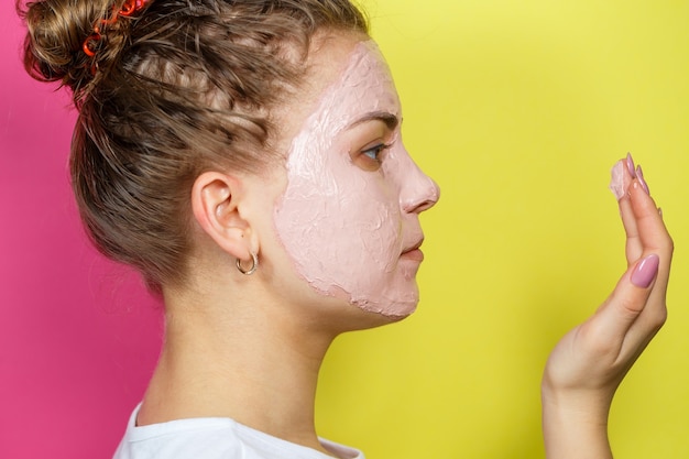 Zdjęcie portret pięknej młodej dziewczyny, która nakłada na twarz odświeżającą maskę, aby odmłodzić i ujędrnić skórę. zabieg upiększający