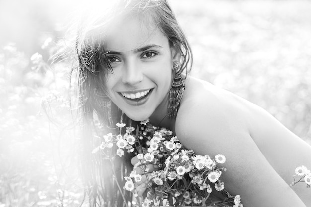 Portret pięknej młodej dziewczyny na wiosnę z polne kwiaty. Szczęśliwe lato twarz młodej kobiety w zielonym polu przyrody.