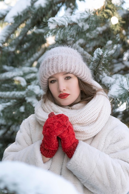 Portret pięknej młodej dziewczyny w zimie w parku na tle ośnieżonych sosen Słoneczny zimowy dzień Pionowa ramka