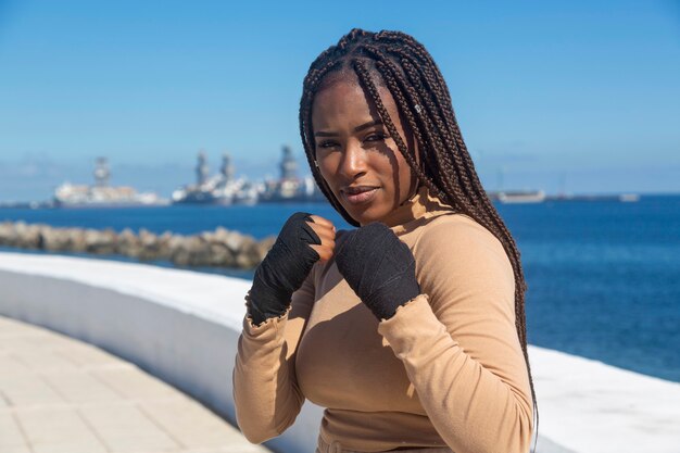Portret pięknej młodej kobiety afro amerykanki z bandażami na rękach do uprawiania sztuk walki, boks.