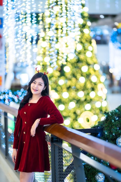 Portret pięknej młodej kobiety azjatyckich czerwona sukienka kostium i Boże Narodzenie powitanie dekoracji paczki na choince światło okrągłe tło bokeh Dekoracja podczas świąt Bożego Narodzenia i Nowego Roku.