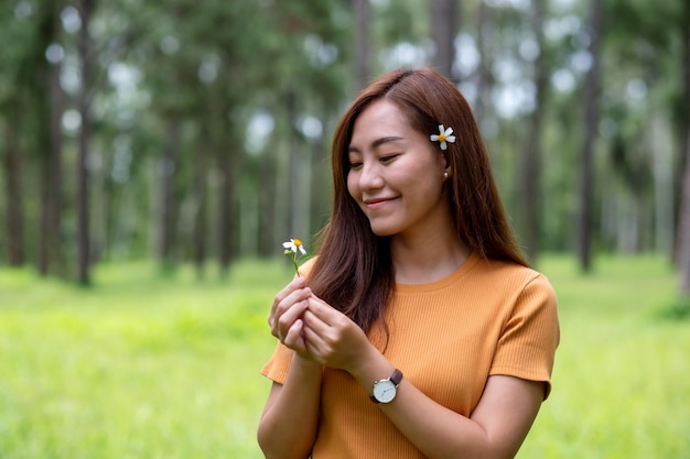 Zdjęcie portret pięknej młodej kobiety azjatyckiej trzymającej kwiat biden alba lub hiszpańskich igieł