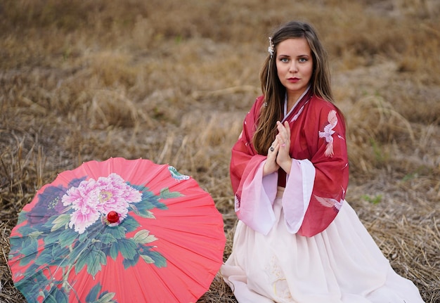 Zdjęcie portret pięknej młodej kobiety siedzącej przy parasolu na lądzie