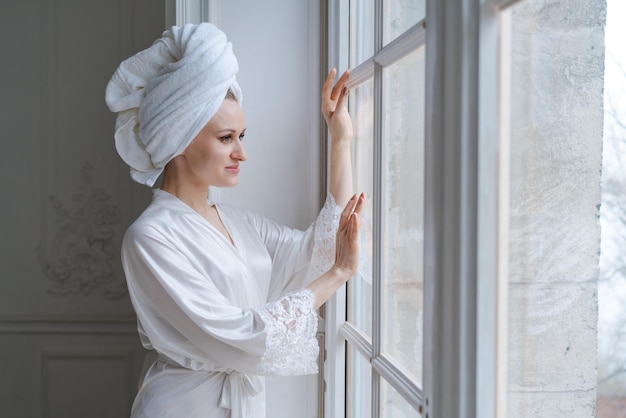 Portret pięknej młodej kobiety ubranej w biały jedwabny szlafrok i ręcznik w turbanie