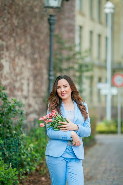 Portret pięknej młodej kobiety w niebieskim garniturze z bukietem tulipanów