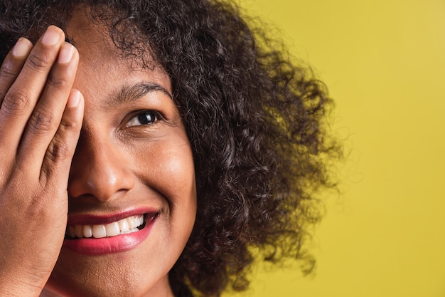 Zdjęcie portret pięknej młodej kobiety w stylu afro stojącej na żółtym tle