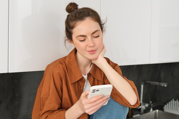 Portret pięknej młodej kobiety ze smartfonem korzystającej z aplikacji mobilnej czytającej wiadomość lub wiadomości na