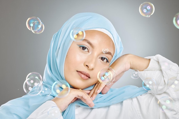 Portret pięknej muzułmańskiej kobiety noszącej niebieską chustę hidżabową na szarym tle Arabska kobieta w szczęśliwym marzeniu i fantazji otoczona czystą rozkoszą i niewinnością figlarnych bąbelków