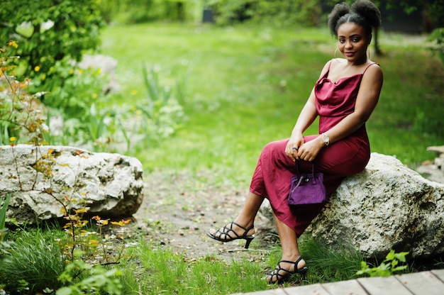 Portret pięknej naturalnej młodej afrykańskiej kobiety z włosami afro. Czarny model w czerwonej jedwabnej sukience.