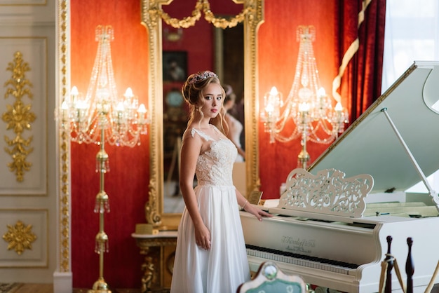 Portret pięknej panny młodej przy fortepianie w luksusowym wnętrzu