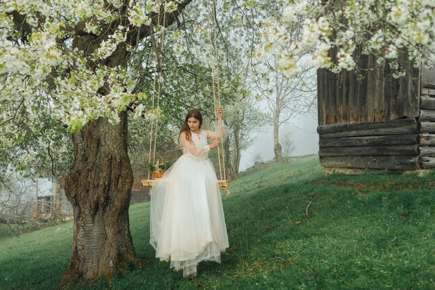 Portret pięknej panny młodej w białej sukni ślubnej uśmiechniętej i kołyszącej się w lesie