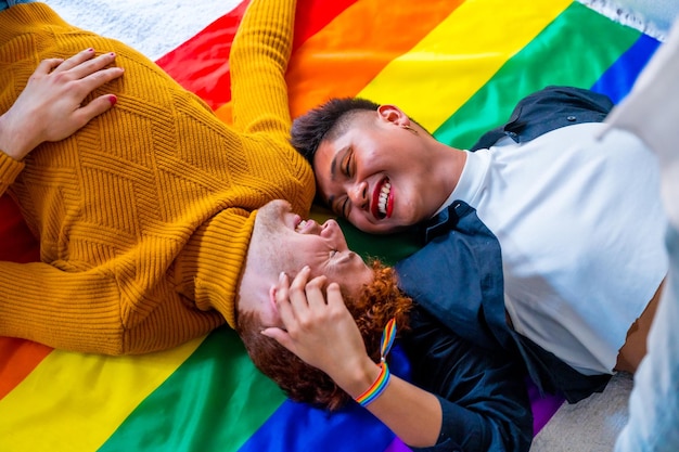Zdjęcie portret pięknej pary gejów, która jest romantyczna w domu nad tęczową flagą koncepcji lgbt