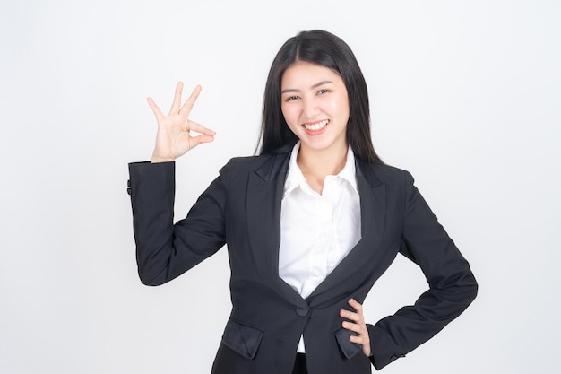 Portret pięknej pracującej azjatyckiej kobiety ze szczęściem pokazującej znak ręki ok dla doskonałości biznesu na białym tle