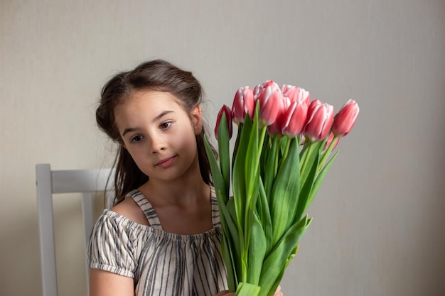 Portret pięknej romantycznej dziewczynki z bukietem różowych tulipanów
