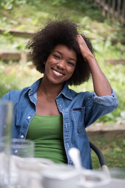 Portret pięknej szczęśliwej afroamerykańskiej dziewczyny siedzącej na zewnątrz
