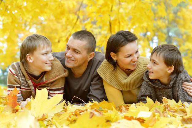 Portret pięknej szczęśliwej rodziny leżącej w jesiennym parku