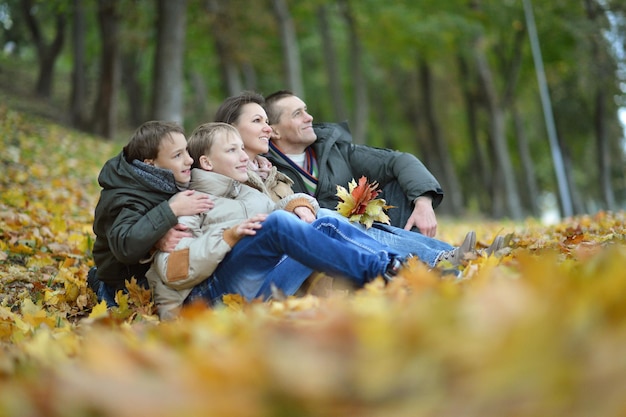Portret pięknej szczęśliwej rodziny siedzącej w jesiennym parku