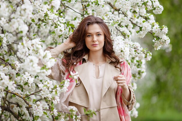 Portret pięknej uśmiechniętej brunetki młodych kobiet w ogrodzie jabłoni kwiat w okresie wiosennym. Ciesz się przyrodą. Zdrowa dziewczyna na zewnątrz. Koncepcja wiosny. Piękna dziewczyna w sadzie