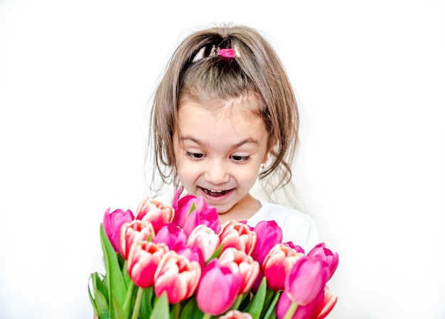 Portret pięknej uśmiechniętej dziewczynki z wiosennymi tulipanami na białym tle