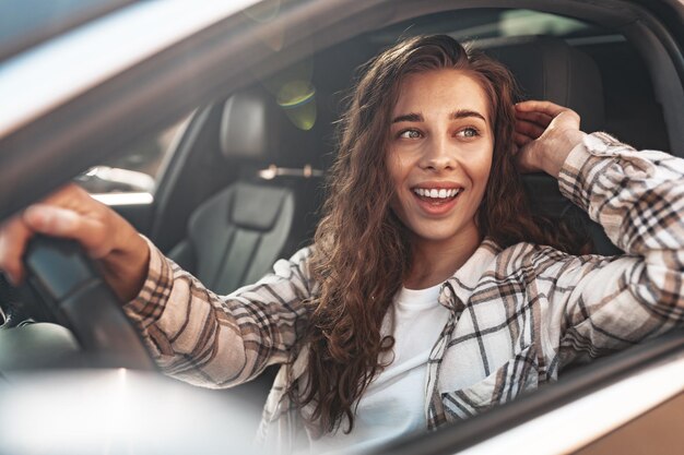Portret pięknej uśmiechniętej kobiety w samochodzie patrząc przez okno