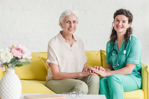 Zdjęcie portret pielęgniarki obsiadanie z starszym żeńskim pacjentem na kanapie