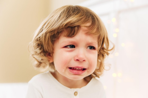 Portret płaczącej dziewczynki. Małe słodkie dziewczyny crying.indoor.curly włosy i niebieskie oczy.