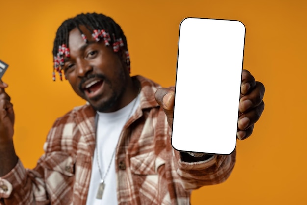 Portret podekscytowanego Afrykanina pokazującego smartfon z białym pustym ekranem w ręku
