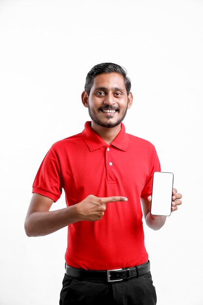 Portret podekscytowany szczęśliwy młody dostawy mężczyzna w czerwonej koszulce i pokazuje smartphone na białym tle.