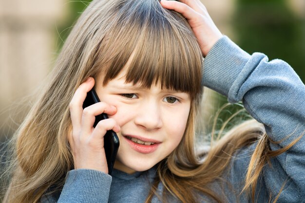 Portret podkreślił dziewczyna dziecko z długimi włosami rozmawia przez telefon komórkowy