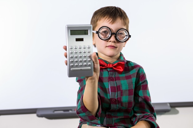 Portret podstawowy chłopiec mienia kalkulator w sala lekcyjnej