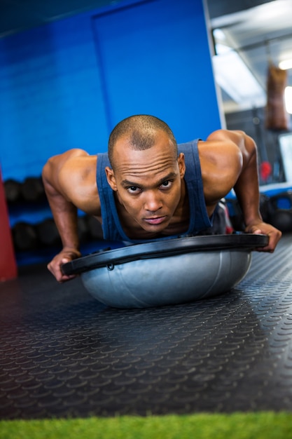 Portret poważna atleta z BOSU piłką w gym