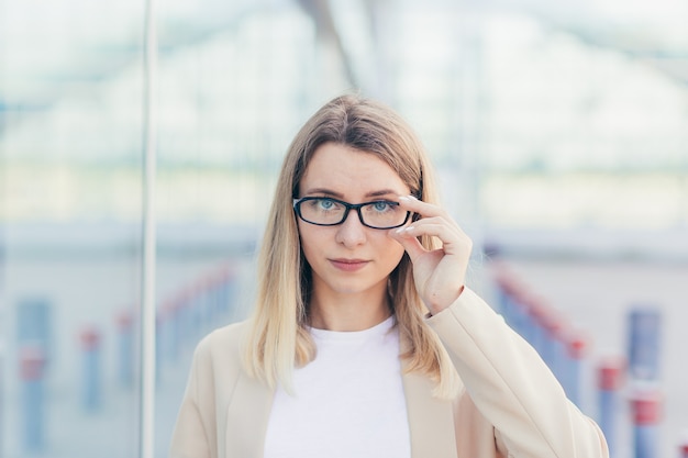 Portret poważnej kobiety biznesu, noszącej blond okulary, patrzącej w kamerę