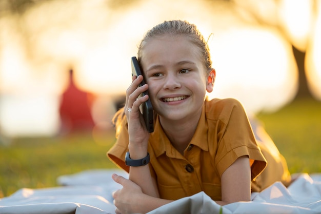 Portret pozytywnego, szczęśliwego dziecka rozmawiającego ze swoją przyjaciółką przez telefon komórkowy