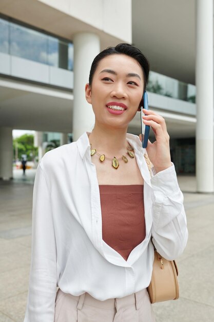 Portret pozytywnej młodej bizneswoman odpowiadającej na telefon od współpracownika